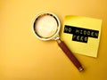 Magnifying glass and sticky note with the text "NO HIDDEN FEES" isolated on yellow background Royalty Free Stock Photo