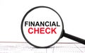 Magnifying glass with text Financial Check on financial tables