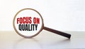 Magnifying glass with text Focus on Quality on wooden table