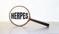 Magnifying glass with text herpes on wooden table