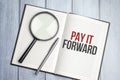 magnifying glass and a white notebook with the text we PAY IT FORWARD Royalty Free Stock Photo