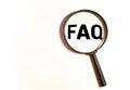 Magnifying glass on wood letters as FAQ abbreviation, frequently asked questions on wooden background