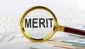 Magnifying glass with the word MERIT on the chart background