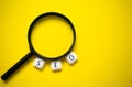 A magnifying glass and the word SEO made with letter game blocks surrounding it, on a bright yellow background. Concept of the Royalty Free Stock Photo