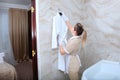 The maid in the bathroom hangs a white Terry-cloth robe on a hanger. The concept of the hotel business. Copy of the Royalty Free Stock Photo