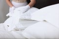 The maid changes the bed linen. Pillows are out of focus. Unrecognizable person. Hands in white cotton gloves. The concept of