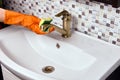 Maid is cleaning brass faucet in bathroom to remove limescale.