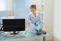 Maid cleaning desk with feather duster