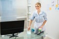 Maid cleaning desk in office Royalty Free Stock Photo