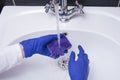 Maid or housewife cleaning wash basin.  WomanÃ¢â¬â¢s gloved hands washing white washbasin. Close-up of hand with sponge. Cleaning Royalty Free Stock Photo