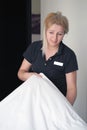Maid making bed in hotel room. Royalty Free Stock Photo