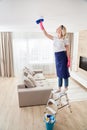 Maid woman holding mop pile, cleaning ceiling in living room. House cleaning service concept. Royalty Free Stock Photo