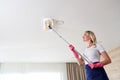 Maid woman holding mop pile, cleaning ceiling in living room. House cleaning service concept.