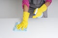 Maid woman wearing gloves cleaning dinning table with cloth rag and detergent spray bottle. Covid-19 Coronavirus prevention