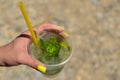 The maiden`s hand holds a transparent glass of ice with lemon and mint. Mojito Royalty Free Stock Photo