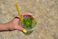 The maiden`s hand holds a transparent glass of ice with lemon and mint. Mojito Royalty Free Stock Photo