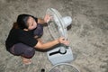 The maidservant is assembling and installing an electric fan after cleaning.