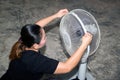 The maidservant is assembling and installing an electric fan after cleaning.