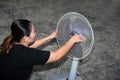 The maidservant is assembling and installing an electric fan after cleaning.