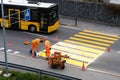 Maienfeld, GR / Switzerland - April 2, 2019: workers painting and marking a pedestrian crosswalk with fresh yellow paint to ensure Royalty Free Stock Photo