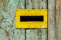 Mail hole with steel yellow painted frame, on wooden fence painted in green