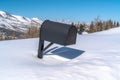 Mailbox half buried in deep snow against mountain and blue sky in Park City