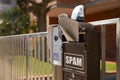 Mailbox with word Spam and newspaper on fence near house