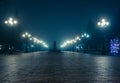 The main alley of a night autumn park in a light fog. Footpath in a fabulous late autumn city park at night with latterns.