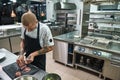 Main dish. Male bald chef with beautiful tattoos on his hands cutting a meat while standing in a restaurant kitchen Royalty Free Stock Photo