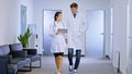The main doctor man and his colleague doctor lady walking in the hospital corridor in front of the using a digital Royalty Free Stock Photo