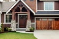 Main entrance door and garage in house. Wooden front door with gabled porch and landing. Exterior of craftsman style home cottage