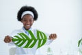 Main focus on green leaf is held by young American African scientist in laboratory or classroom