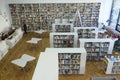 Main hall of the public library, shelves with books and magazines, visitors and librarians working