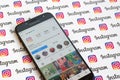 Main official instagram account on smartphone screen on paper instagram banner