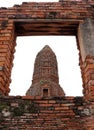 The Main Phra Prang or pagoda, the view through the window of church in the ruins of ancient remains at Wat Worachet temple. Royalty Free Stock Photo