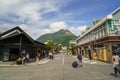 Main road from train station filled with tourists, streetscape and local shops direct to fresh green Yufudake mountain peak and bl Royalty Free Stock Photo