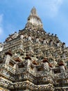 The main spire at the Wat Arun Temple, the Temple of Dawn, with its intricite facade of color is stretching towards a blue sky in