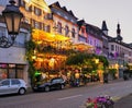 Main street at night in the town of Cochem, Germany on the Mosel River. Glowing lights, restaurants, parked cars, people flowers.