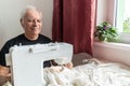 Old male man senior sit next at table at home work, sewing machine enjoy Royalty Free Stock Photo