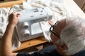 Old male man senior sit next at table at home work, sewing machine enjoy Royalty Free Stock Photo