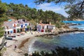 Main view of cala s`Alguer, a lovely beach surrounded by traditional fishermen`s white buildings with colorful doors and windows.