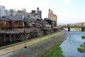 Main view of Kamo river promenade with many terraces of restaurants and bars with Kyoto`s old town buildings on background