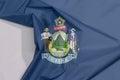 Maine fabric flag crepe and crease with white space. Maine coat of arms defacing blue field Royalty Free Stock Photo