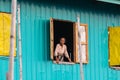 Maing Thauk, Myanmar - April 2019: old Burmese woman looking out of the floating house window Royalty Free Stock Photo