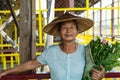 Maing Thauk, Myanmar - April 2019: portrait of an old Burmese woman in a bamboo hat and flowers Royalty Free Stock Photo