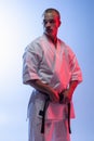 One young professional karate, judo sportsman in white kimono isolated over gradient white blue background