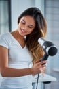 Maintaining her healthy hair from root to tip. an attractive young woman blowdrying her hair in the bathroom.