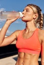 Maintaining hydration. A woman drinks water during a workout, replenishing her water-salt balance, beautiful light, a