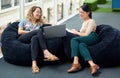 Maintaining innovation through their collaboration. two businesswomen using a laptop together while sitting on beanbags Royalty Free Stock Photo