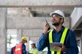 Maintenance manager using walkie-talkie to communicate safety and quality control policy with workers on site, civil engineer Royalty Free Stock Photo